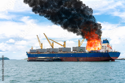 Large general cargo ship for logistic import export goods and other the explosion and had a lot of fire and smoke at sea in bright day photo