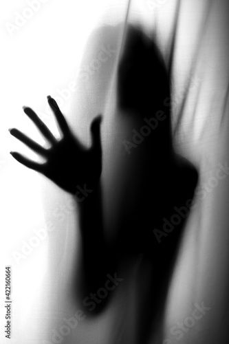 Silhouette of girl behind a curtain. Blurry hand and body figure abstract. Black and white picture