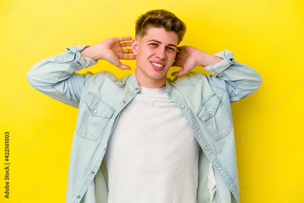 Young caucasian man isolated on yellow background stretching arms, relaxed position. Young caucasian man isolated on yellow background stretching arms, relaxed position.