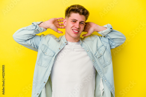 Young caucasian man isolated on yellow background stretching arms, relaxed position.