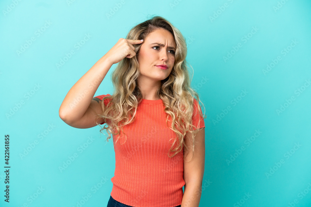 Young Brazilian woman isolated on blue background making the gesture of madness putting finger on the head Young Brazilian woman isolated on blue background making the gesture of madness putting finger on the head