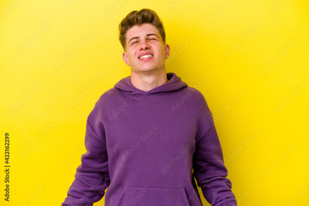 Young caucasian man isolated on yellow background relaxed and happy laughing, neck stretched showing teeth. Young caucasian man isolated on yellow background relaxed and happy laughing, neck stretched showing teeth.