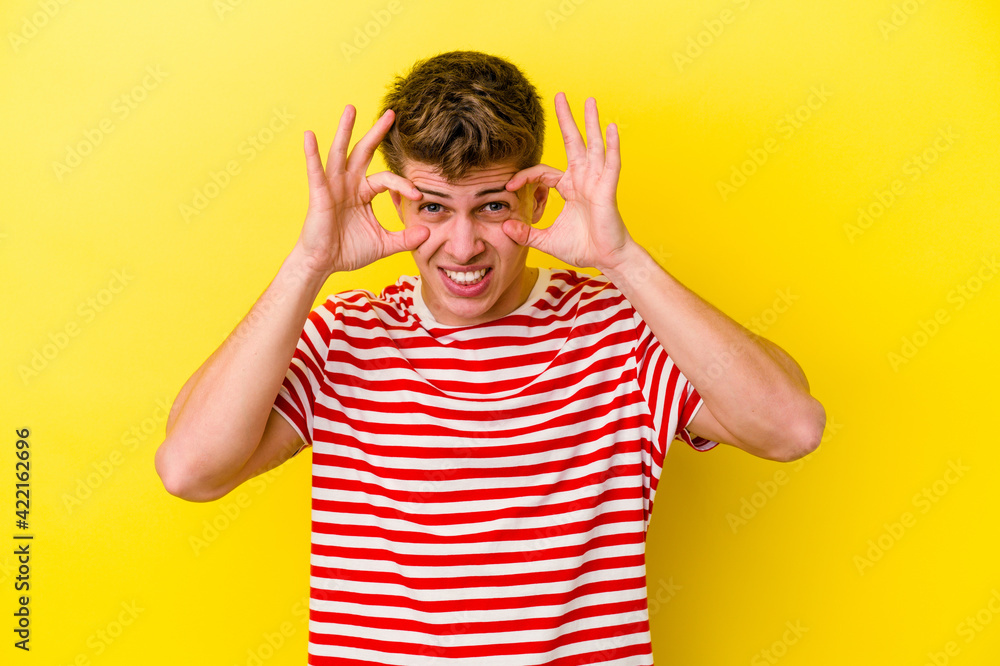 Young caucasian man isolated on yellow background keeping eyes opened to find a success opportunity. Young caucasian man isolated on yellow background keeping eyes opened to find a success opportunity.