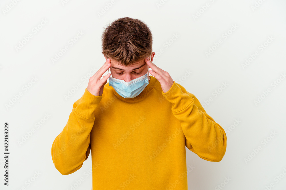 Young man wearing a mask for coronavirus isolated on white background touching temples and having headache. Young man wearing a mask for coronavirus isolated on white background touching temples and having headache.