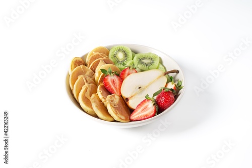 Bowl with pancakes, strawberries, pear, kiwi and peanut butter