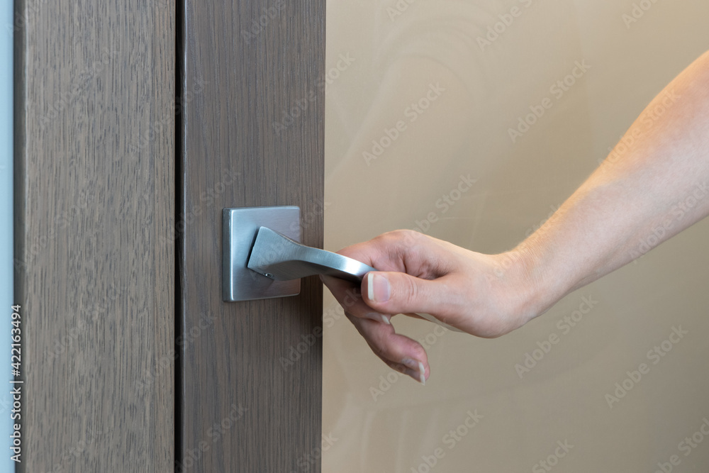 Woman opens or closes door. Close-up of hand opening door, unrecognizable person. Only hand is visible. Home life concept. Horizontal