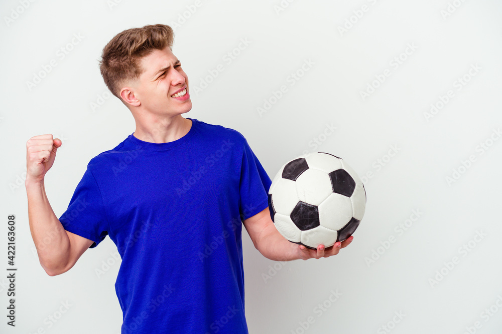 Young caucasian man playing soccer isolated on background raising fist after a victory, winner concept. Young caucasian man playing soccer isolated on background raising fist after a victory, winner concept.