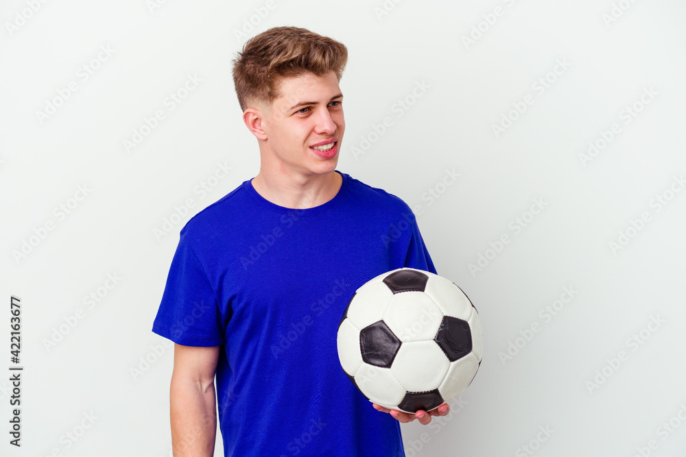 Young caucasian man playing soccer isolated on background looks aside smiling, cheerful and pleasant.