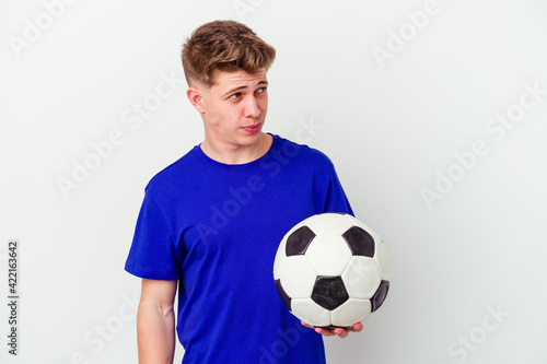 Young caucasian man playing soccer isolated on background confused, feels doubtful and unsure.