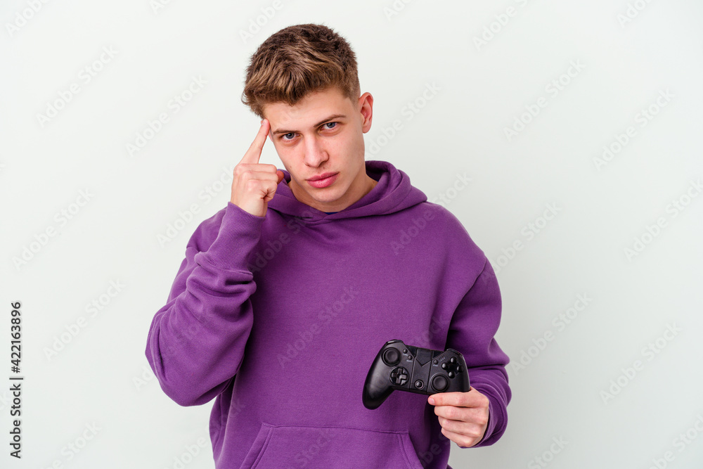 Young caucasian man holding a gamepad isolated on white background pointing temple with finger, thinking, focused on a task. Young caucasian man holding a gamepad isolated on white background pointing temple with finger, thinking, focused on a task.