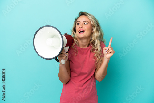 Young Brazilian woman isolated on blue background holding a megaphone and intending to realizes the solution