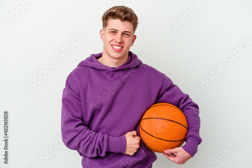 Young caucasian man playing basketball isolated background laughing and having fun.