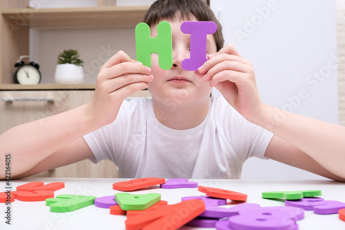 A friendly boy showing a word Hi made of colorful letters, introduction and friendship concept