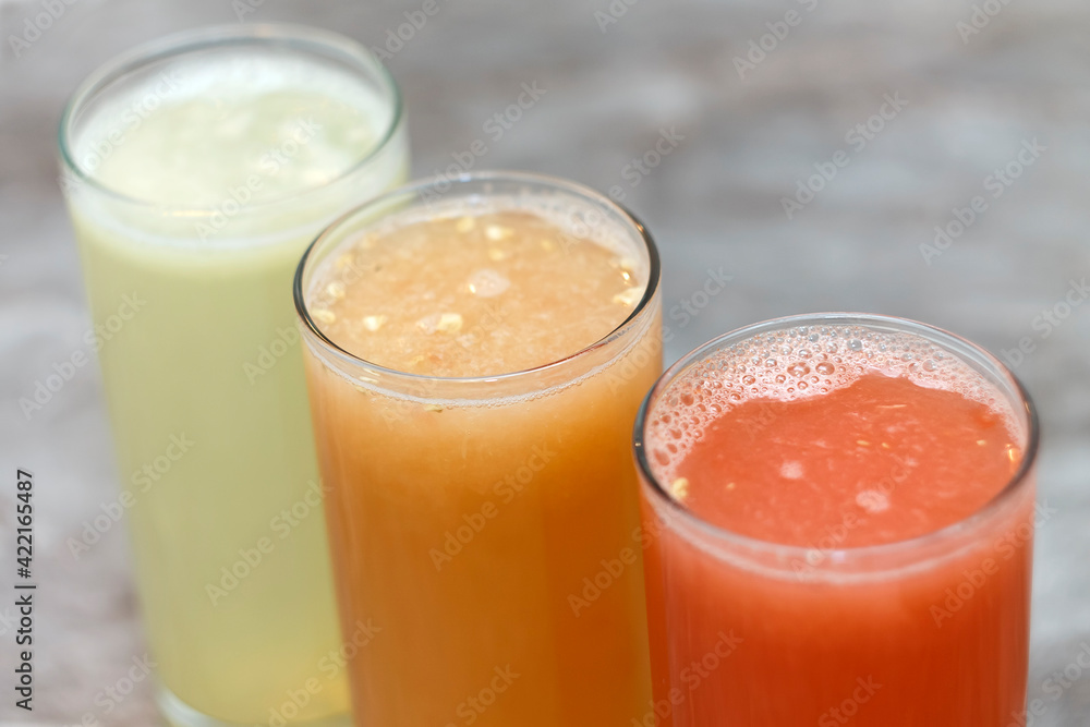 Tthree glasses of juice from different fresh squeezed fruits Tthree glasses of juice from different fresh squeezed fruits