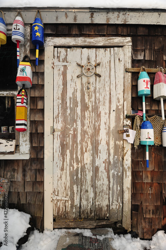 Weather beaten and worn doorway of a lobsterman's fishing shack with colorful buoys photo