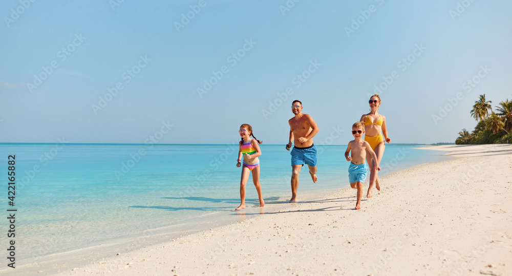 Happy family running on tropical beach