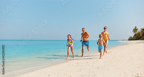 Happy family running on tropical beach