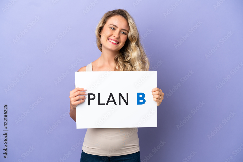 Young Brazilian woman isolated on purple background holding a placard with the message PLAN B with happy expression Young Brazilian woman isolated on purple background holding a placard with the message PLAN B with happy expression