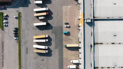 Bilde på lerret Numerous different trucks stand on parking site near huge warehouse buildings at