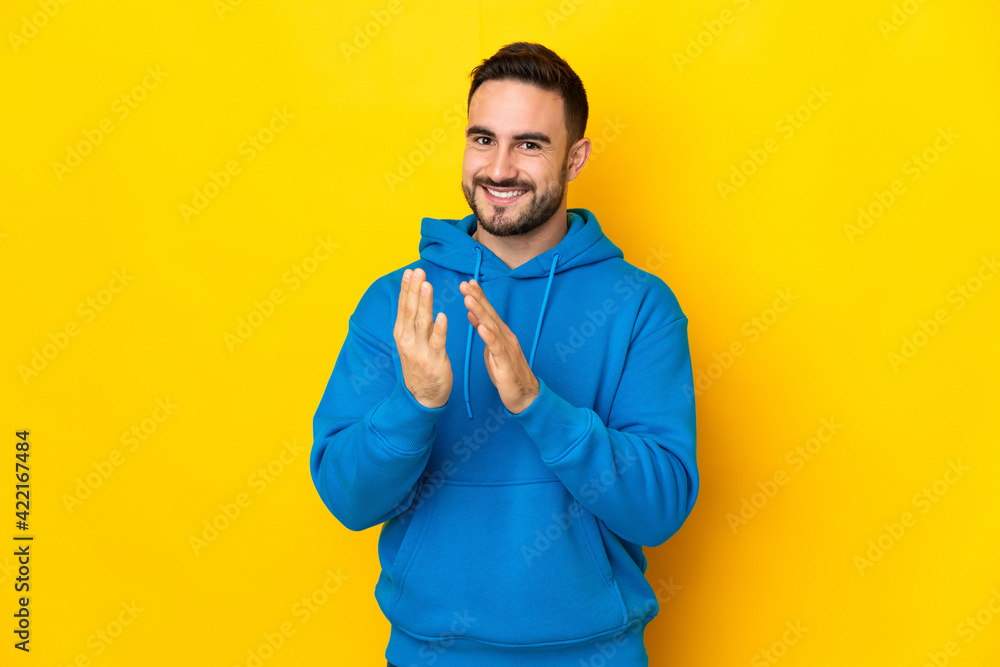 Young caucasian handsome man isolated on yellow background applauding after presentation in a conference Young caucasian handsome man isolated on yellow background applauding after presentation in a conference