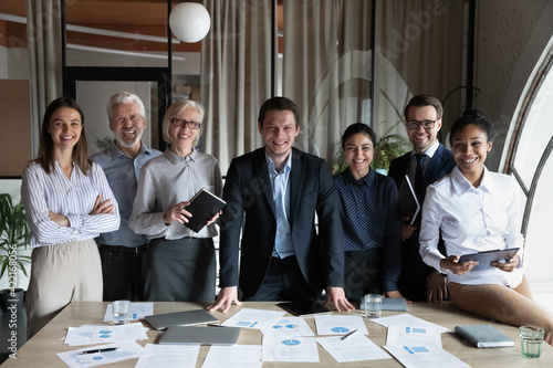 Portrait of happy multiracial businesspeople stand pose at workplace in modern office. Smiling diverse multiethnic employees colleagues show leadership unity. Success, employment concept.