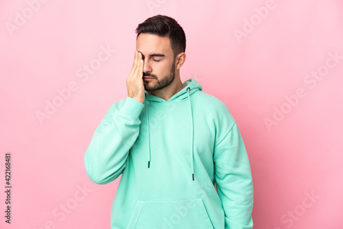 Young caucasian handsome man isolated on pink background with headache © luismolinero
