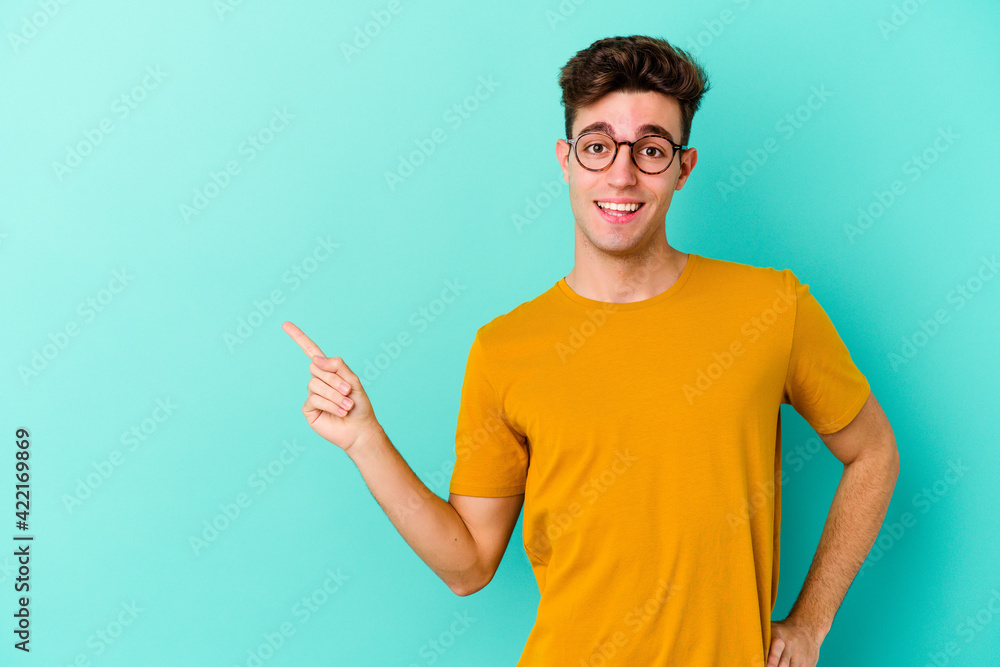 Young caucasian man isolated on blue background smiling cheerfully pointing with forefinger away. Young caucasian man isolated on blue background smiling cheerfully pointing with forefinger away.