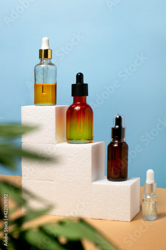 Pipette cosmetics bottles in a row on natural beige and blue background. Set of cube geometric stairs product promo