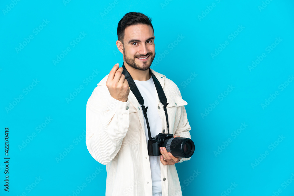 Young photographer man isolated on blue background making money gesture Young photographer man isolated on blue background making money gesture