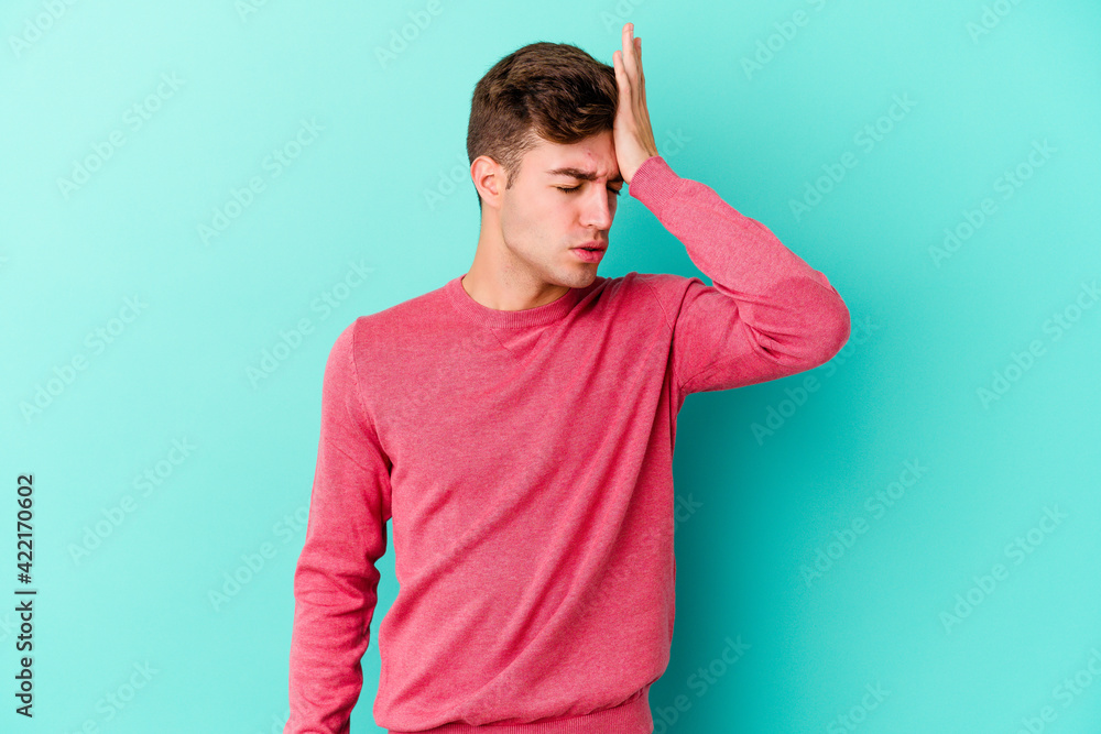 Young caucasian man isolated on blue background forgetting something, slapping forehead with palm and closing eyes. Young caucasian man isolated on blue background forgetting something, slapping forehead with palm and closing eyes.