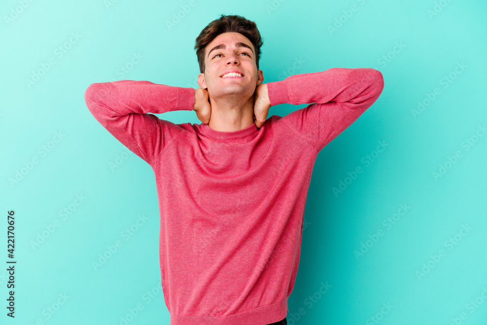 Young caucasian man isolated on blue background feeling confident, with hands behind the head. Young caucasian man isolated on blue background feeling confident, with hands behind the head.
