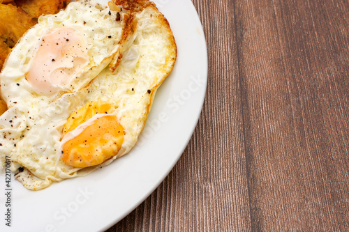 Huevos fritos en plato blanco sobre mesa de madera. Comida hecha en casa, saludable