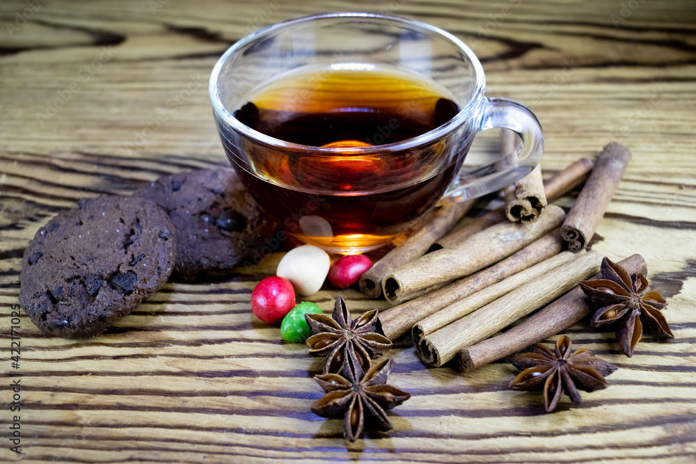 image of a cup of tea, anise, cinnamon, chocolate chip cookies and sweets on a wooden table