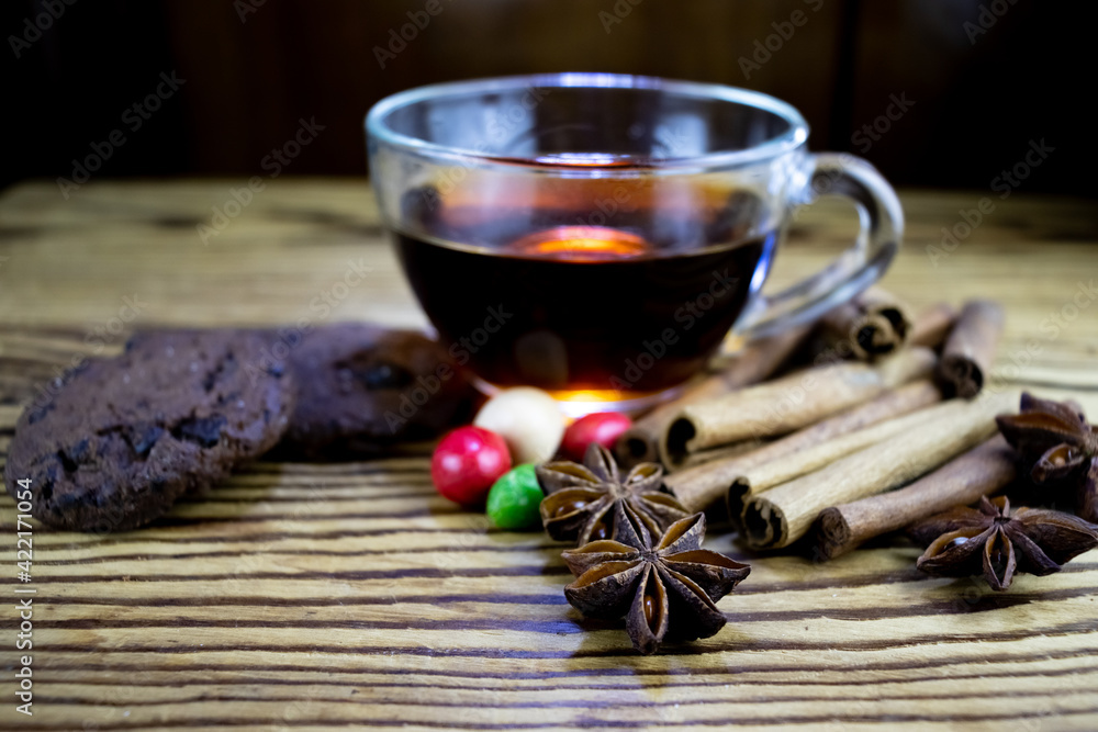 image of a cup of tea, anise, cinnamon, chocolate chip cookies and sweets on a wooden table image of a cup of tea, anise, cinnamon, chocolate chip cookies and sweets on a wooden table