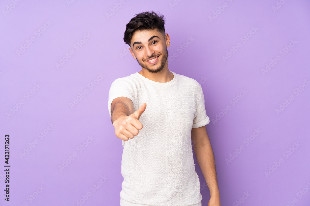 Fototapeta premium Arabian handsome man over isolated background with thumbs up because something good has happened