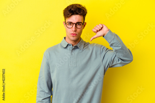 Young caucasian man isolated on yellow background showing a dislike gesture  thumbs down. Disagreement concept.