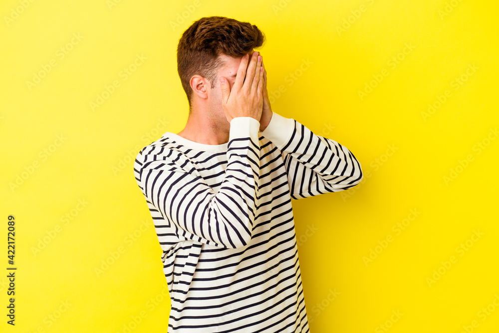 Young caucasian man isolated on yellow background afraid covering eyes with hands. Young caucasian man isolated on yellow background afraid covering eyes with hands.