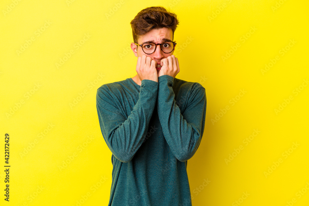 Fototapeta premium Young caucasian man isolated on yellow background biting fingernails, nervous and very anxious.