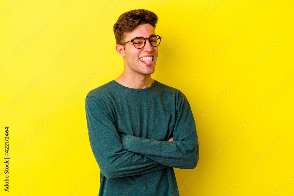 Young caucasian man isolated on yellow background funny and friendly sticking out tongue. Young caucasian man isolated on yellow background funny and friendly sticking out tongue.