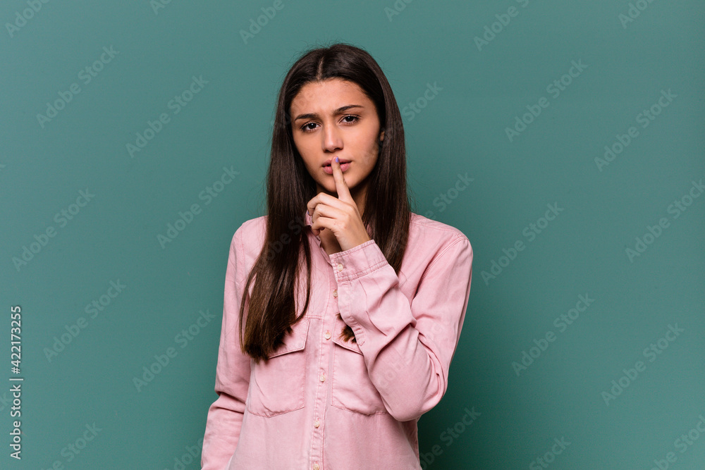 Young Indian woman isolated on blue background keeping a secret or asking for silence. Young Indian woman isolated on blue background keeping a secret or asking for silence.