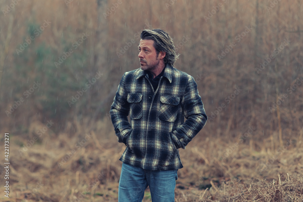 Man in checkered coat in rainy woodland. Man in checkered coat in rainy woodland.