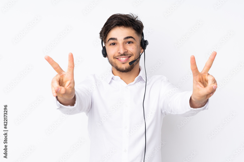 Telemarketer Arabian man working with a headset isolated on white background smiling and showing victory sign Telemarketer Arabian man working with a headset isolated on white background smiling and showing victory sign
