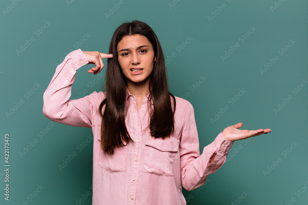 Young Indian woman isolated on blue background holding and showing a product on hand. Young Indian woman isolated on blue background holding and showing a product on hand.