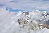 The mountain ranges are covered with snow and clouds. Snowy mountain peaks on a sunny winter day. Scenic Mountain landscape from the top of the mountain. Climbing mountain summits among the clouds.
