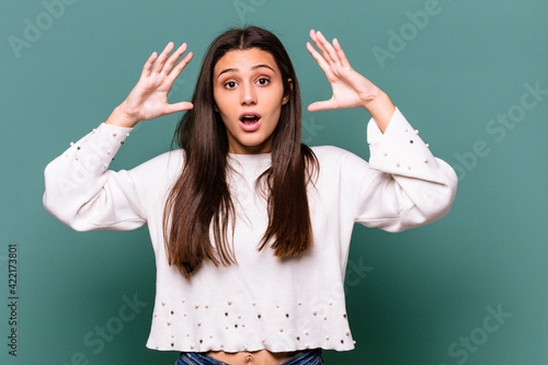 Young Indian woman isolated on blue background celebrating a victory or success, he is surprised and shocked.