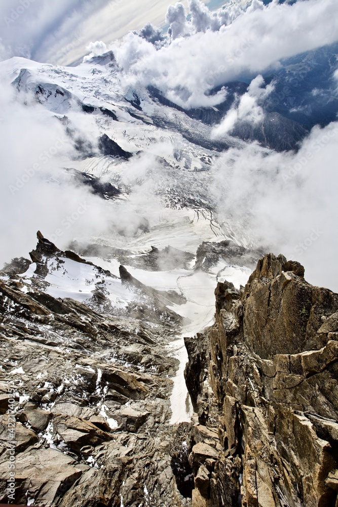 Obraz premium The mountain ranges are covered with snow and clouds. Snowy mountain peaks on a sunny winter day. Scenic Mountain landscape from the top of the mountain. Climbing mountain summits among the clouds.