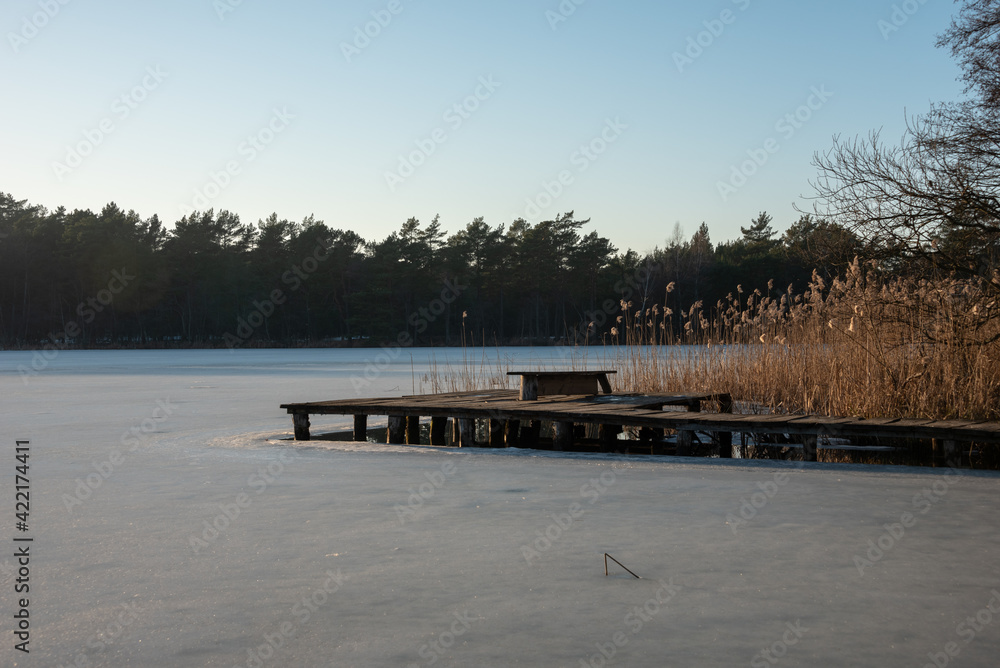 Typical polish winter landscape. Old wooden bridge on the frozen lake. Selective focus. Typical polish winter landscape. Old wooden bridge on the frozen lake. Selective focus.