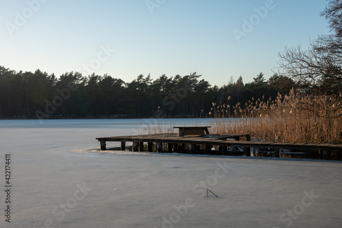 Typical polish winter landscape. Old wooden bridge on the frozen lake. Selective focus.  photo