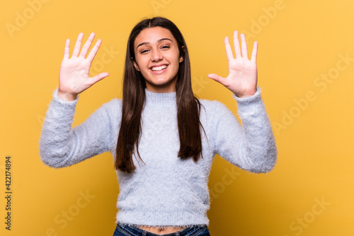 Young Indian woman isolated on yellow background showing number ten with hands.
