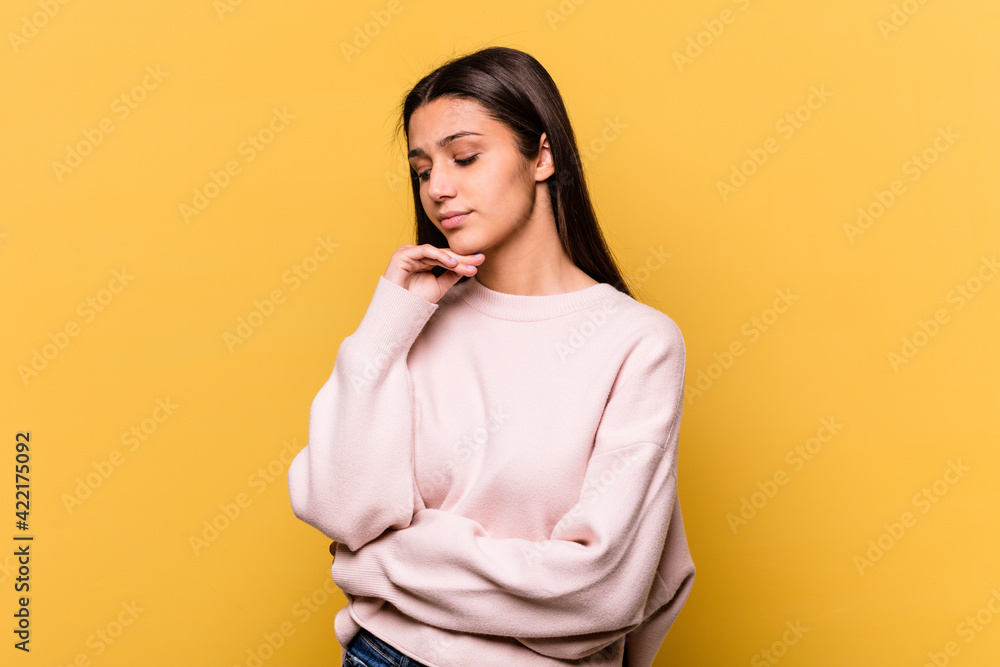 Obraz premium Young Indian woman isolated on yellow background looking sideways with doubtful and skeptical expression.